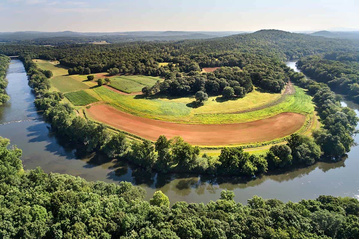 Aerial view of contemporary home tucked into wooded riverfront property
