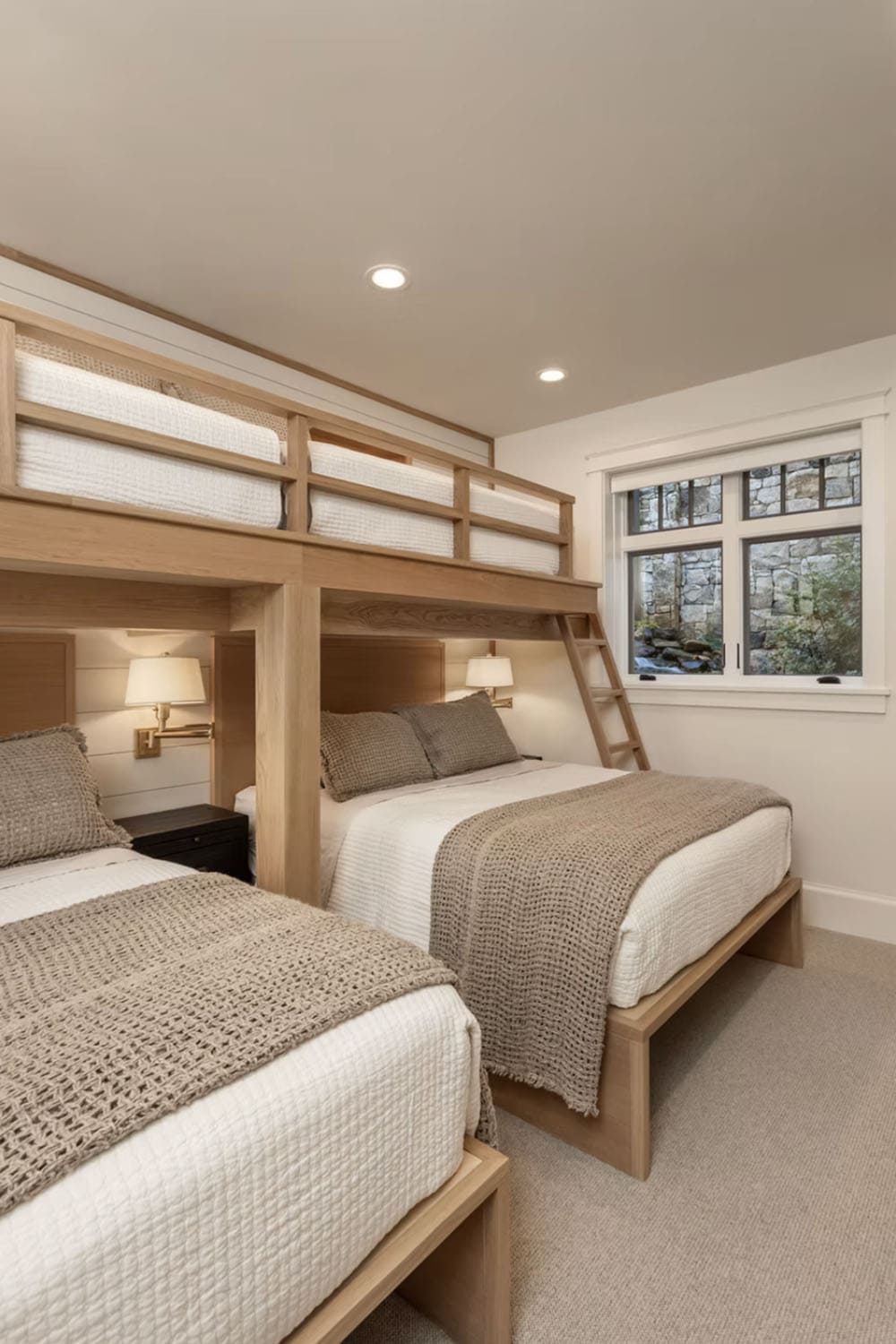 Bunk room with custom light wood built-in bunk beds over two full-size beds and wall sconces