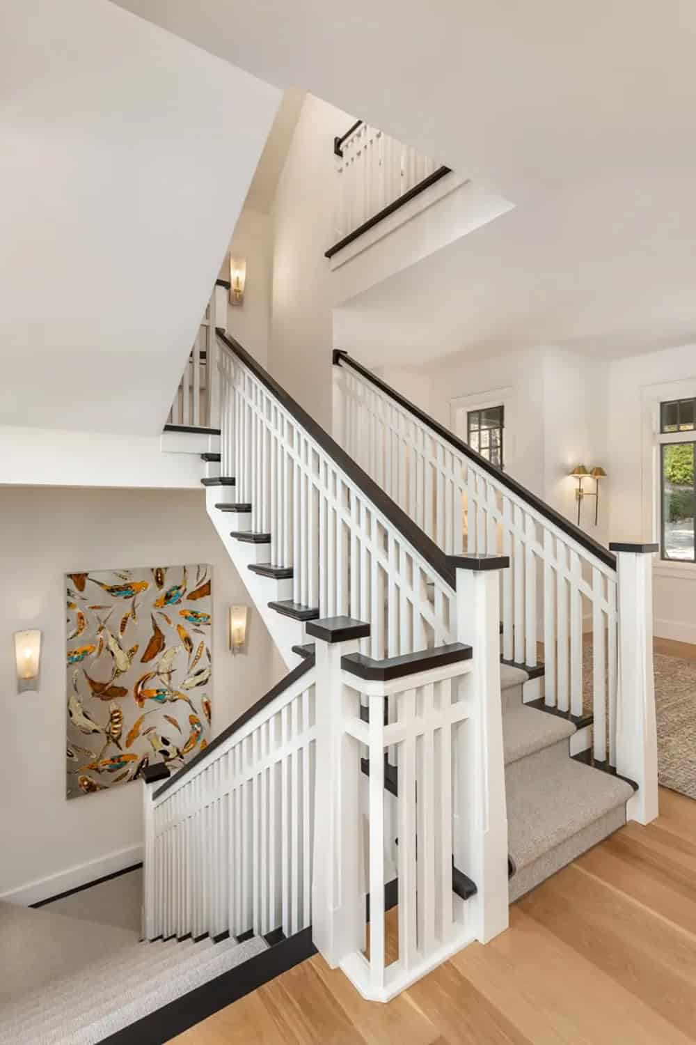 White staircase with dark treads and balusters, carpeted runner, and colorful koi fish artwork