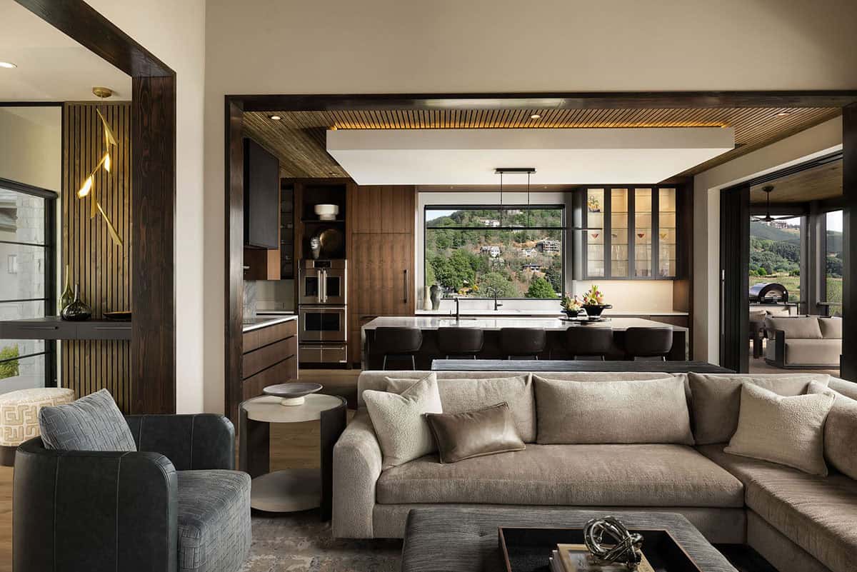 Open concept living space with dark walnut kitchen, two-tone wood slat ceiling detail, and sweeping mountain views through large windows
