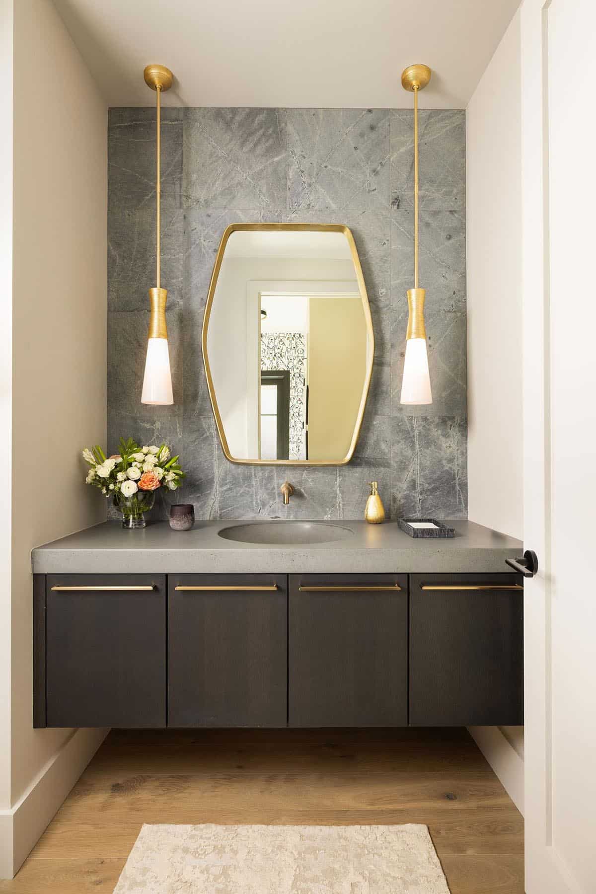 Powder room with floating dark vanity, concrete countertop, green stone slab feature wall, and paired brass pendant lights