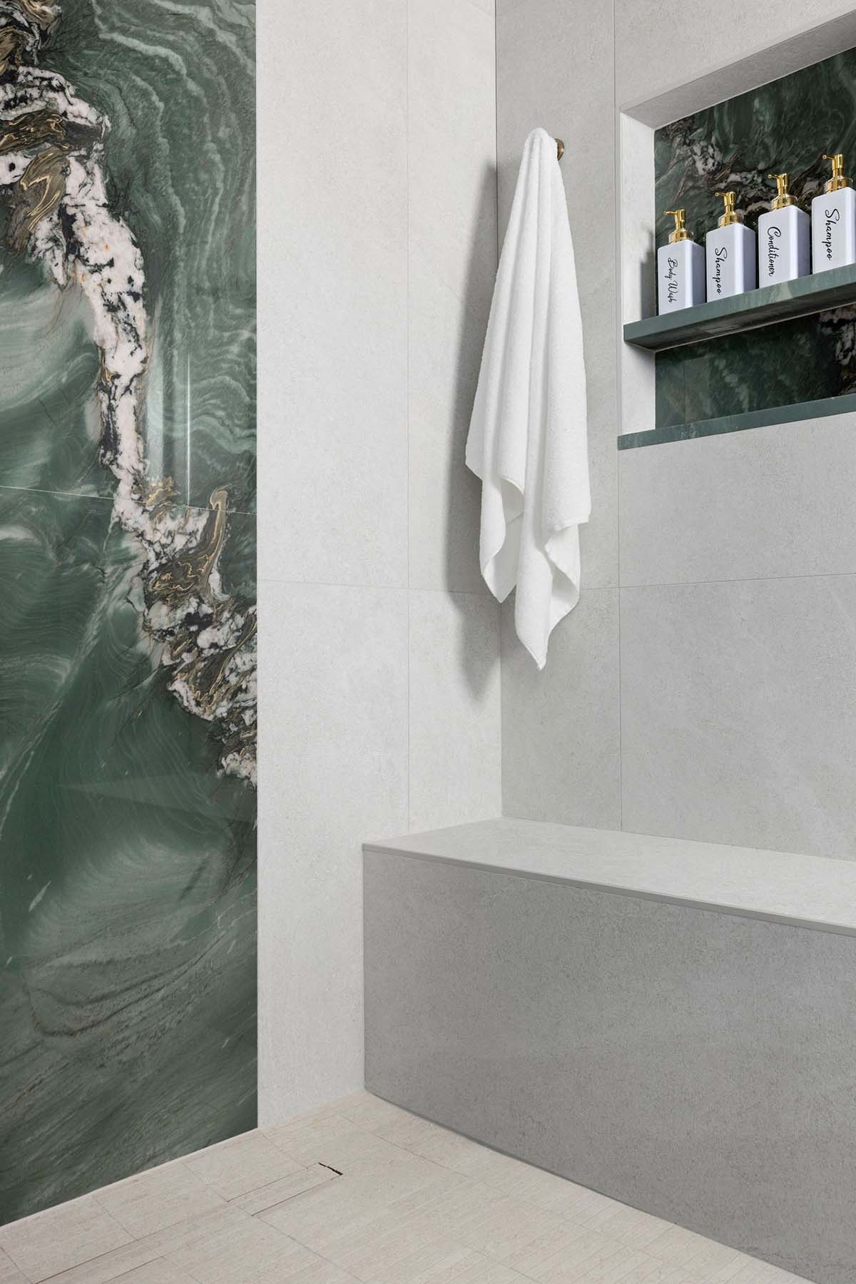 Modern walk-in shower with green marble accent wall and built-in niche