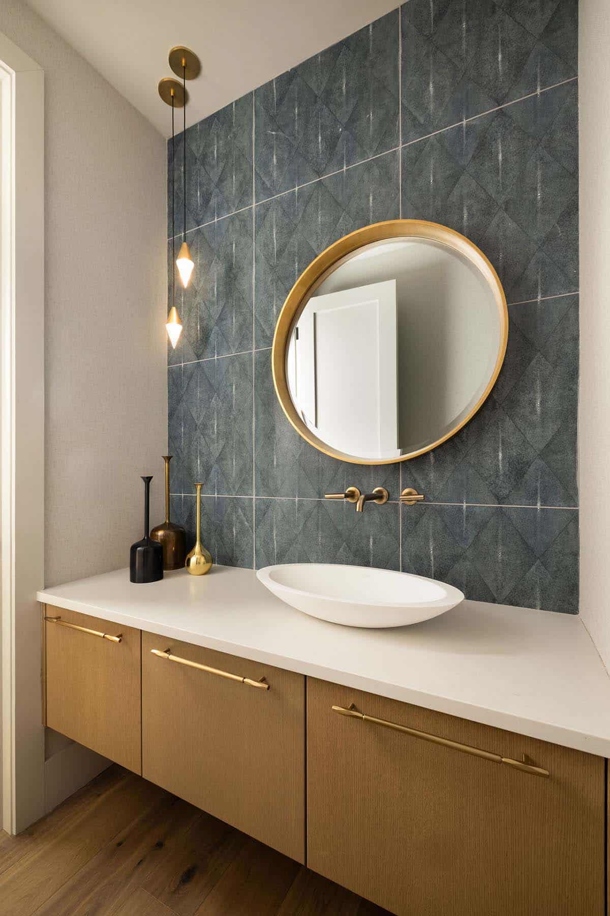 powder room, vessel sink, floating vanity, brass hardware, gold round mirror, blue geometric tile accent wall, pendant lights, wall-mount faucet