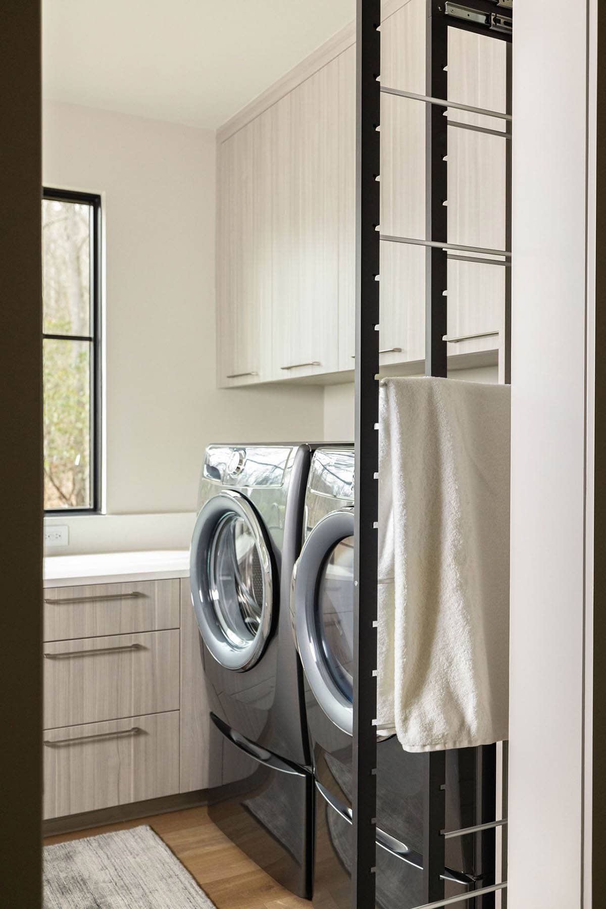 laundry room, pull-out drying rack, front-load washer dryer, light cabinetry
