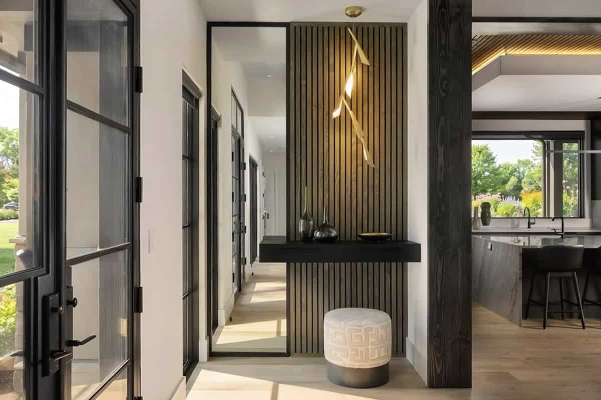 entryway, wood slat accent wall, leaning mirror, black floating console, branch pendant light, steel-framed glass doors, dark wood beam