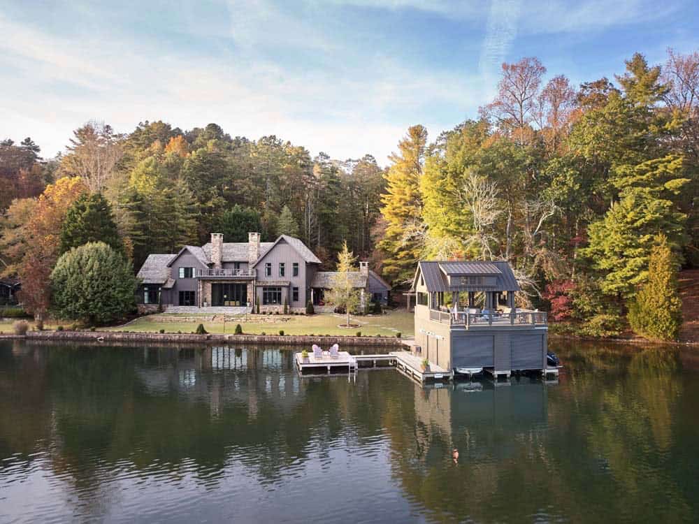Contemporary rustic lake house viewed from the water with boathouse and fall foliage