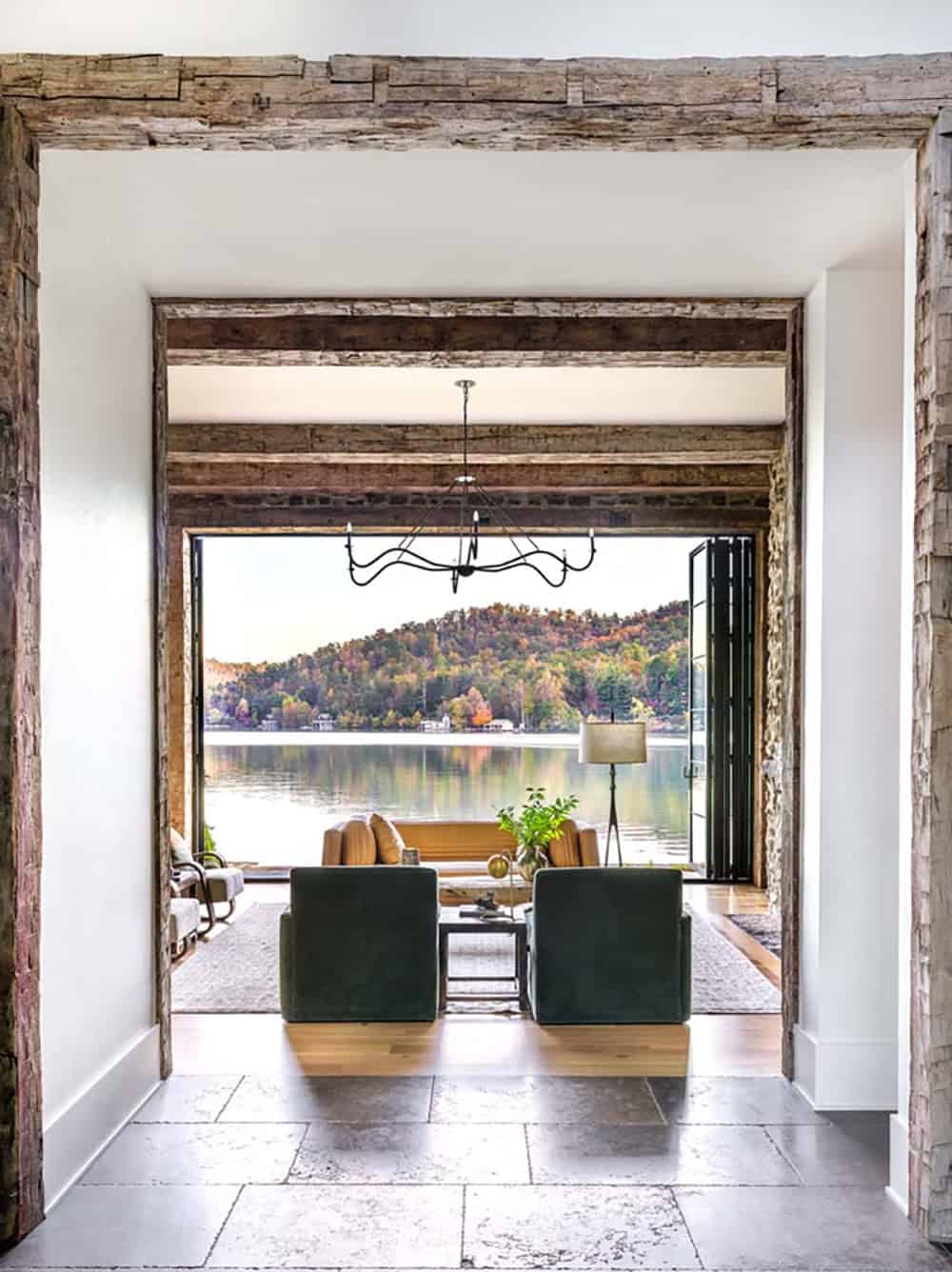 Foyer with reclaimed wood beam surround framing lake view through open living room