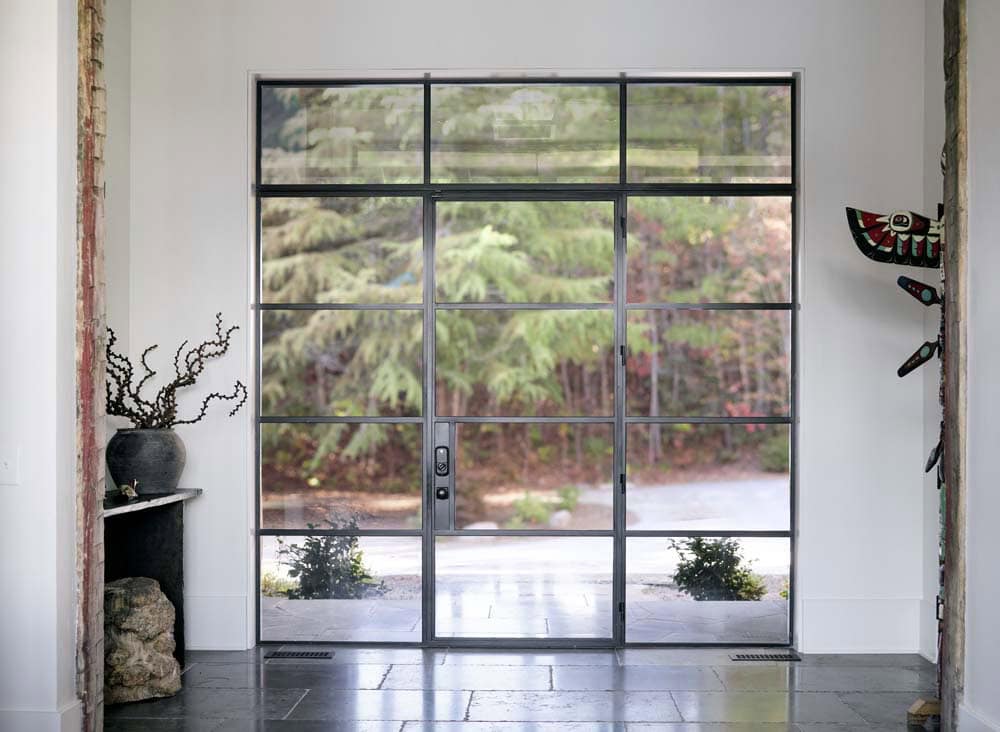 Interior steel-frame glass entry door with sidelights in white foyer