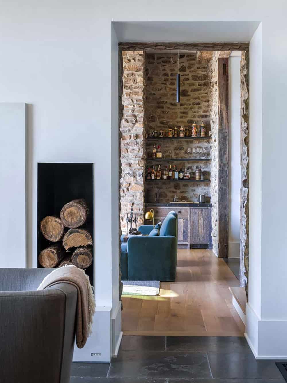 Hallway view into rustic bar niche with stone walls and open shelving