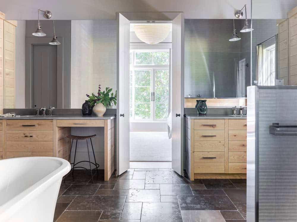 Primary bathroom with dual oak vanities, freestanding tub, and slate tile floor