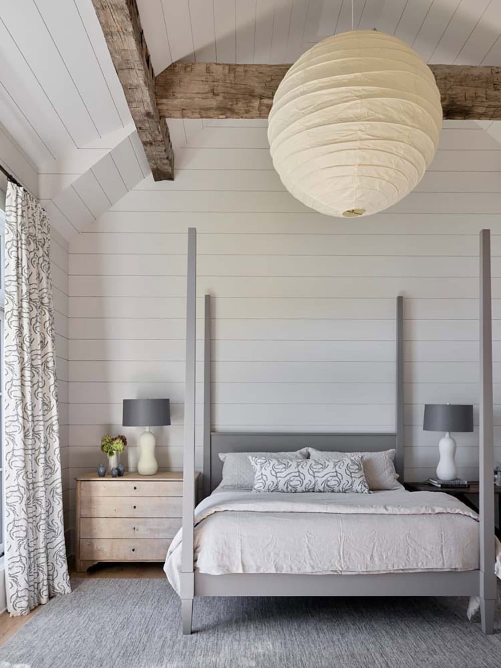 Primary bedroom with four-poster bed, shiplap walls, exposed beams, and globe pendant light