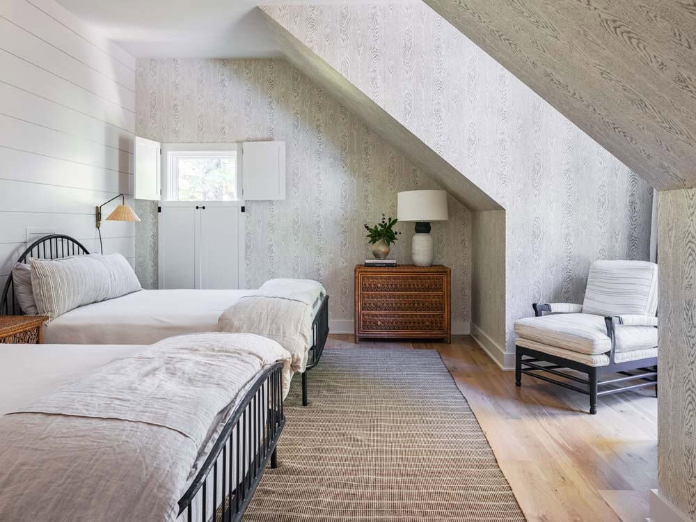Attic guest bedroom with twin beds, sloped ceiling, and textured wallpaper
