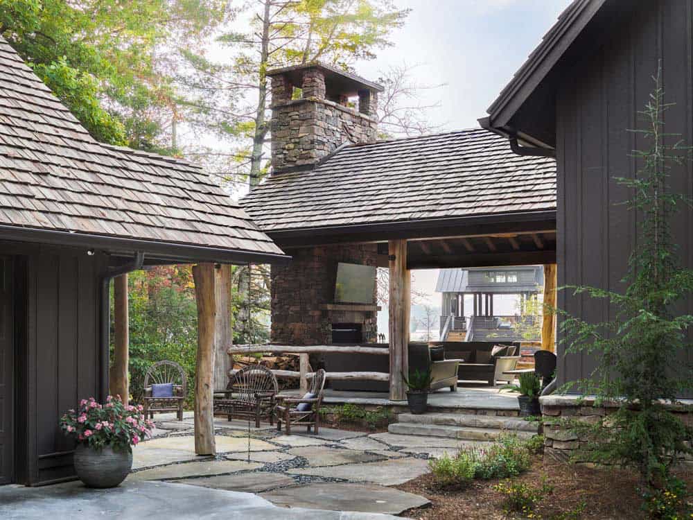 Covered outdoor living pavilion with stone fireplace, timber posts, and flagstone patio