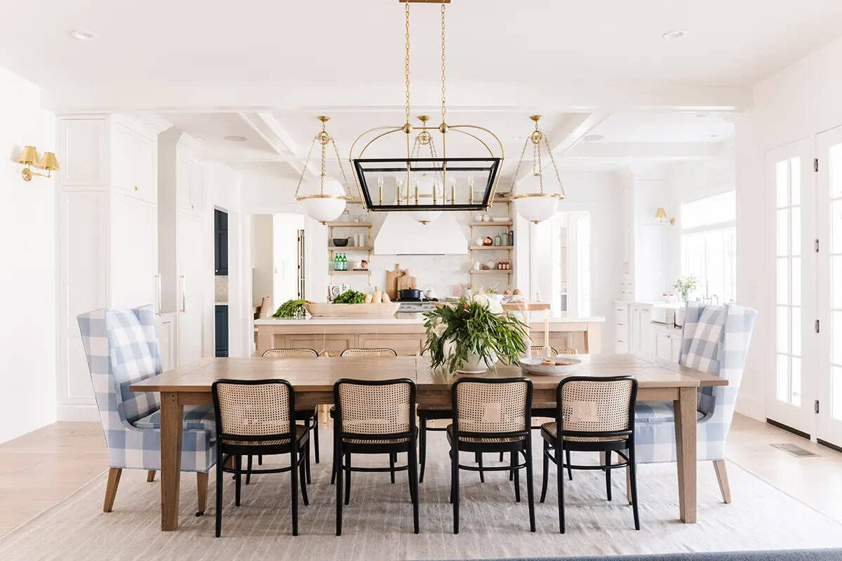 Dining room with plaid wingback chairs, cane chairs, wood table, and brass lantern pendant
