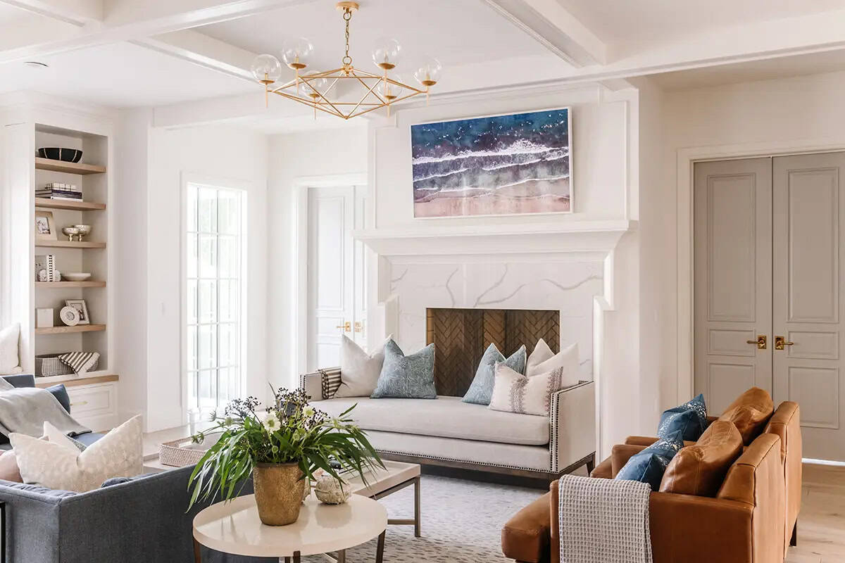 Bright living room with marble fireplace, blue and cream sofas, leather chairs, and gold chandelier