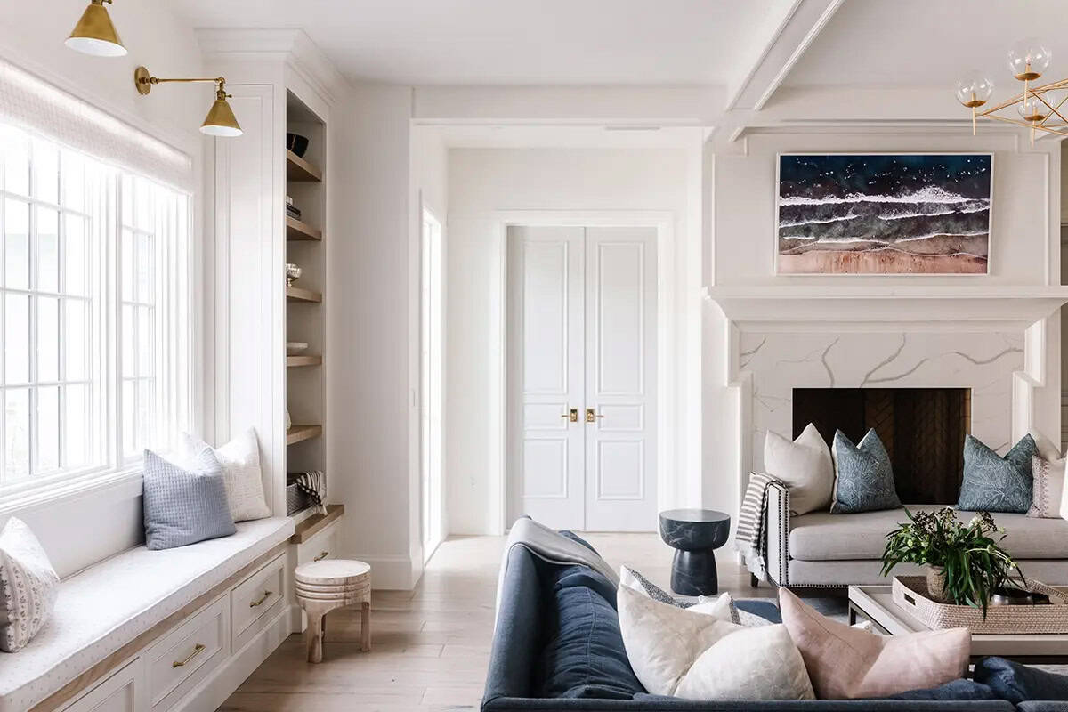 Living room with window seat, built-in shelves, marble fireplace, and blue velvet sofa