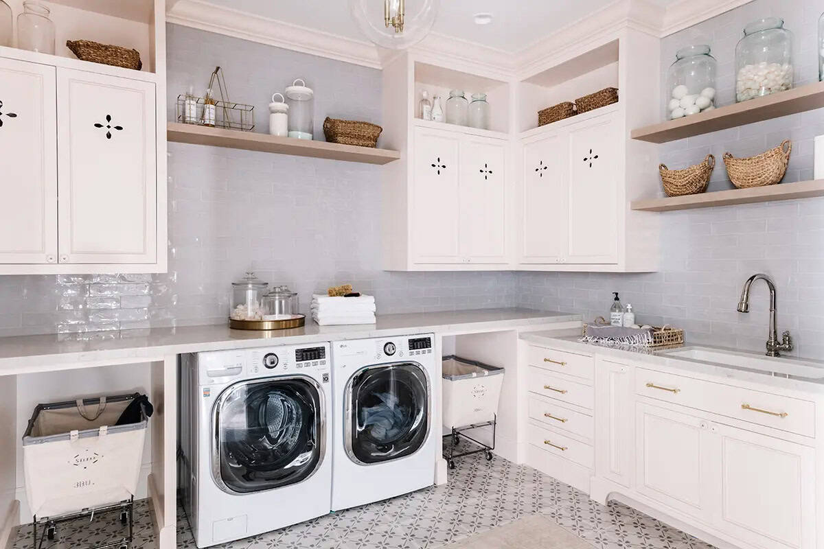 White laundry room with front-load washer and dryer, open shelving, and patterned tile floor