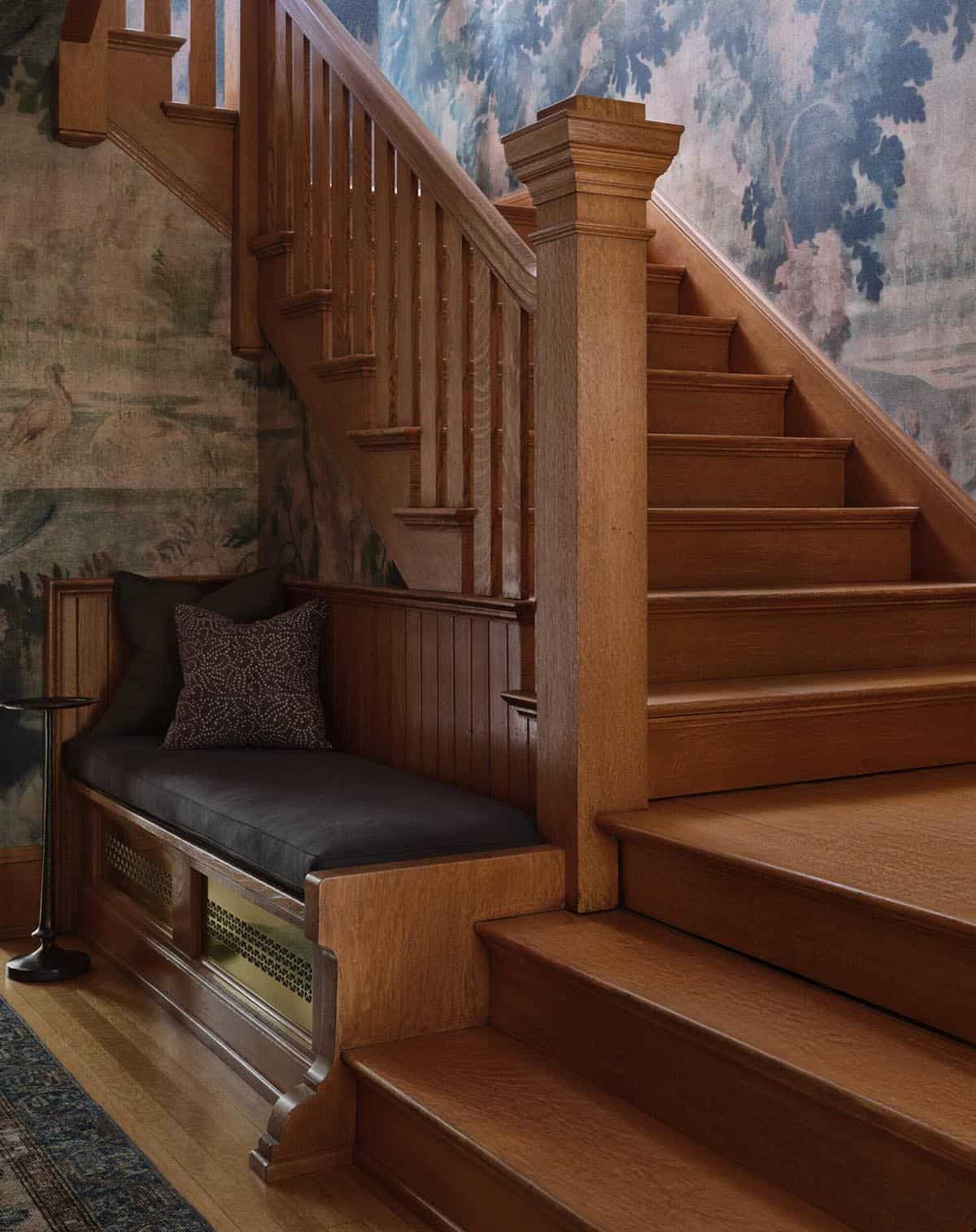 Oak staircase close-up with built-in bench seat, dark cushion, and scenic mural wallpaper