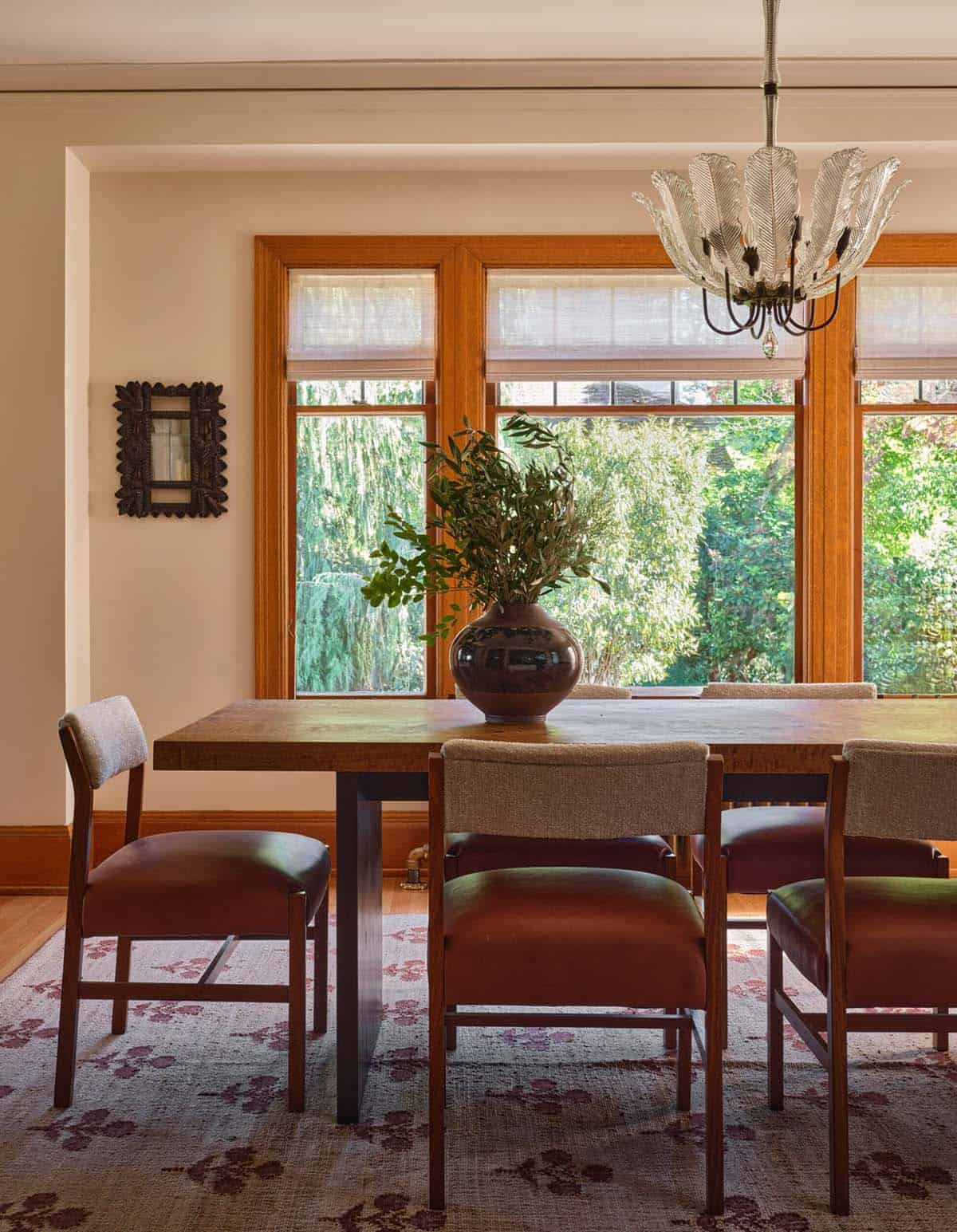 Dining room with wood table, rust leather chairs, glass leaf chandelier, and garden views
