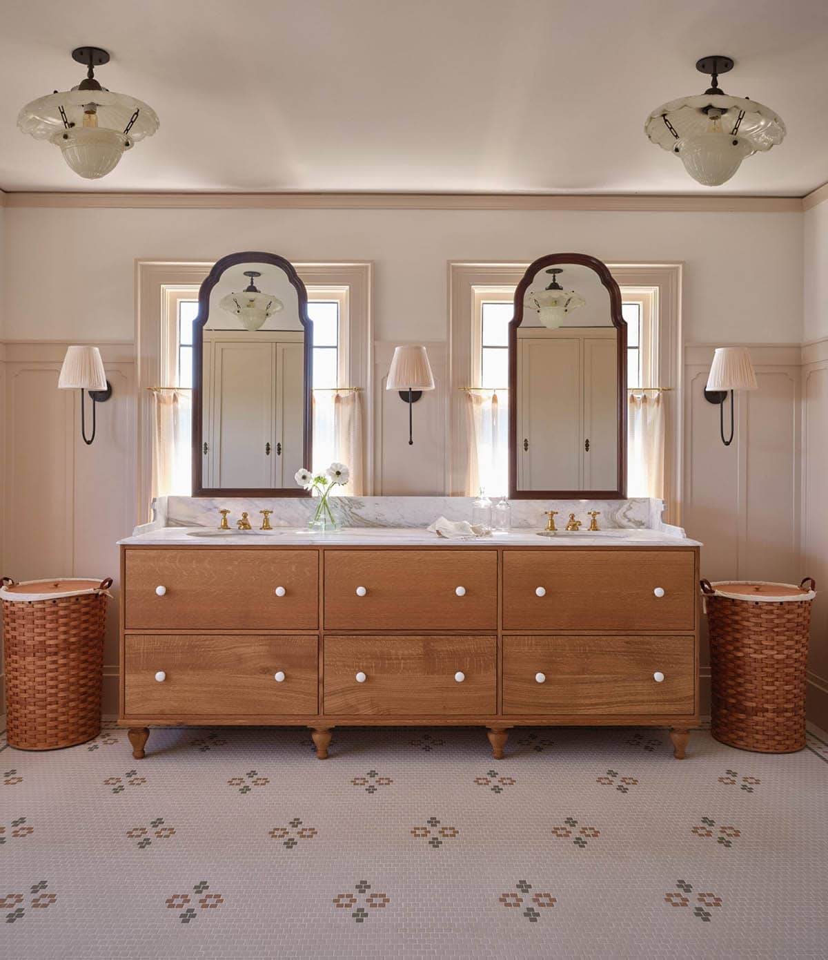 Double vanity with two arched mirrors, oak dresser cabinet, mosaic tile floor, and scalloped pendant lights