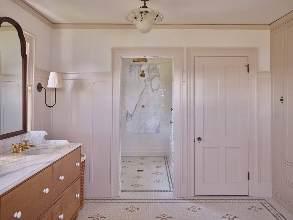 Primary bathroom with pink paneled walls, wood vanity, mosaic tile floor, and open shower entry
