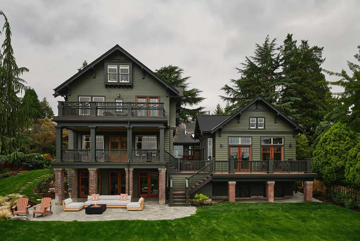 Rear exterior of green craftsman farmhouse with multi-level decks, patio seating, and fire pit