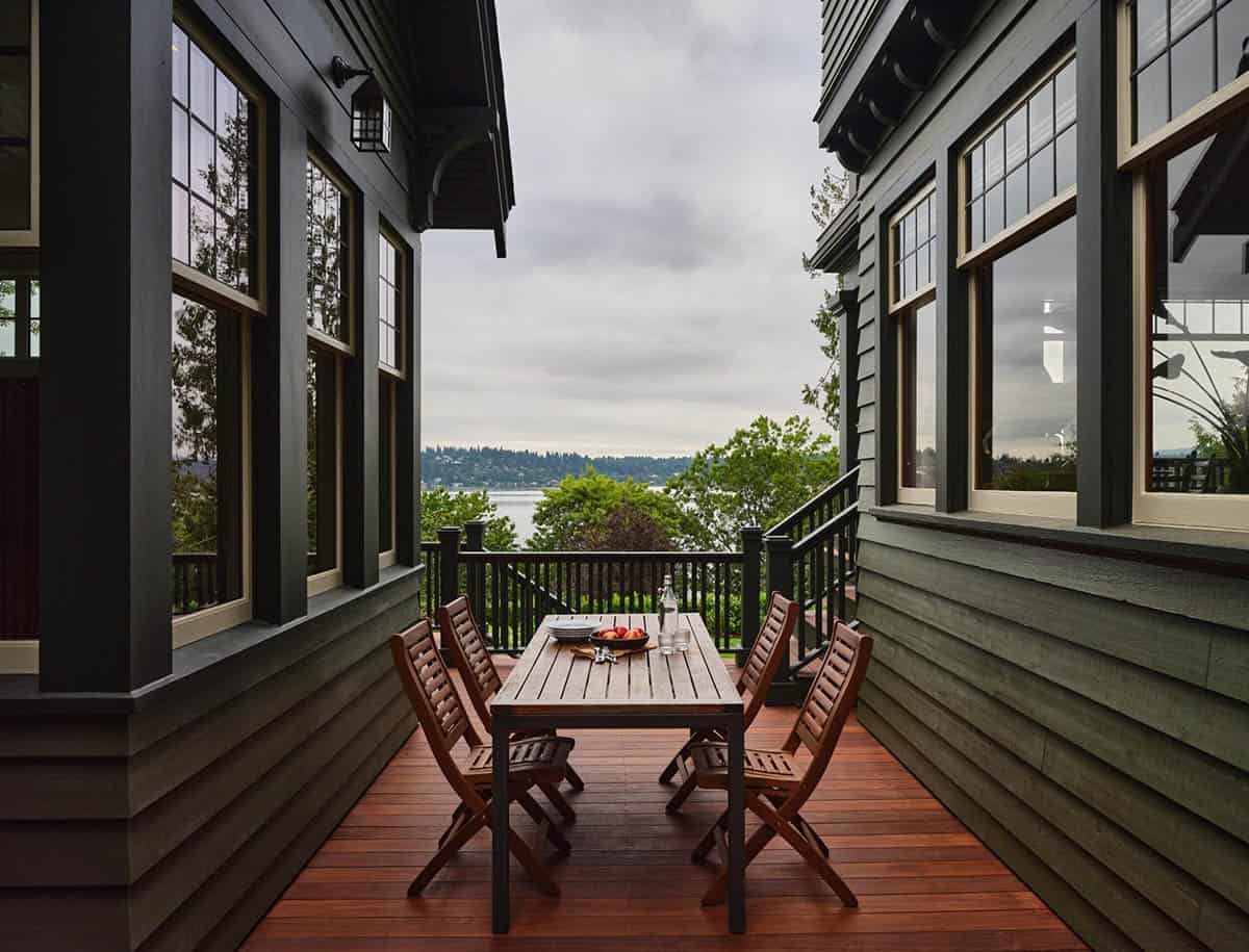 Deck dining area with teak table and chairs overlooking lake and treetop views