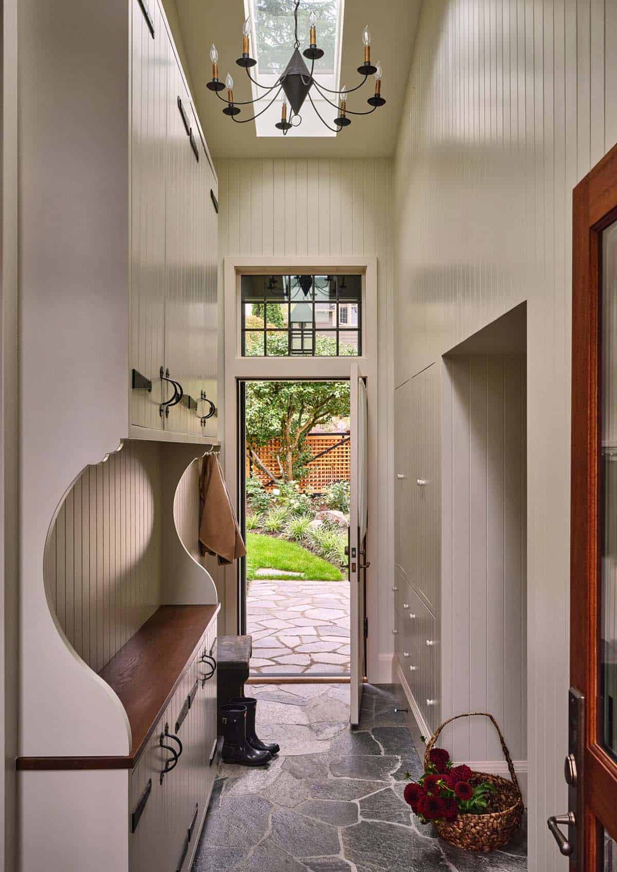 Mudroom with beadboard walls, built-in bench, coat hooks, slate floor, and iron chandelier