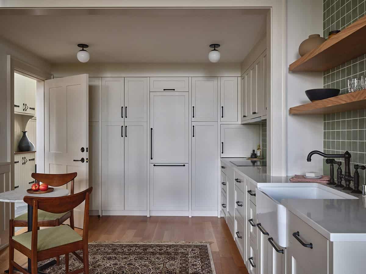 Guest cottage kitchen with white shaker cabinets, green tile backsplash, farmhouse sink, and open shelving