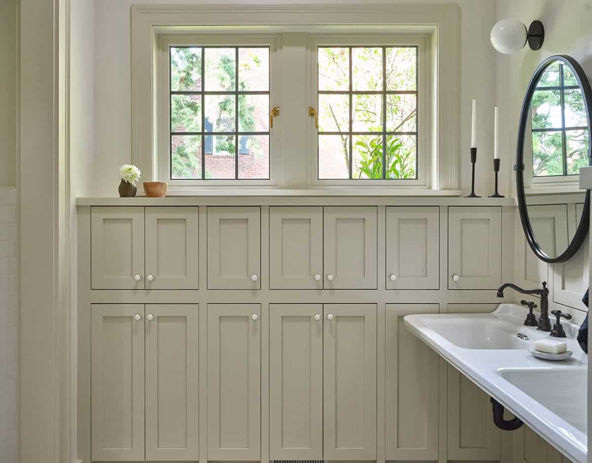 Bathroom storage wall with cream shaker cabinets, white knobs, garden window, and a white sink basin