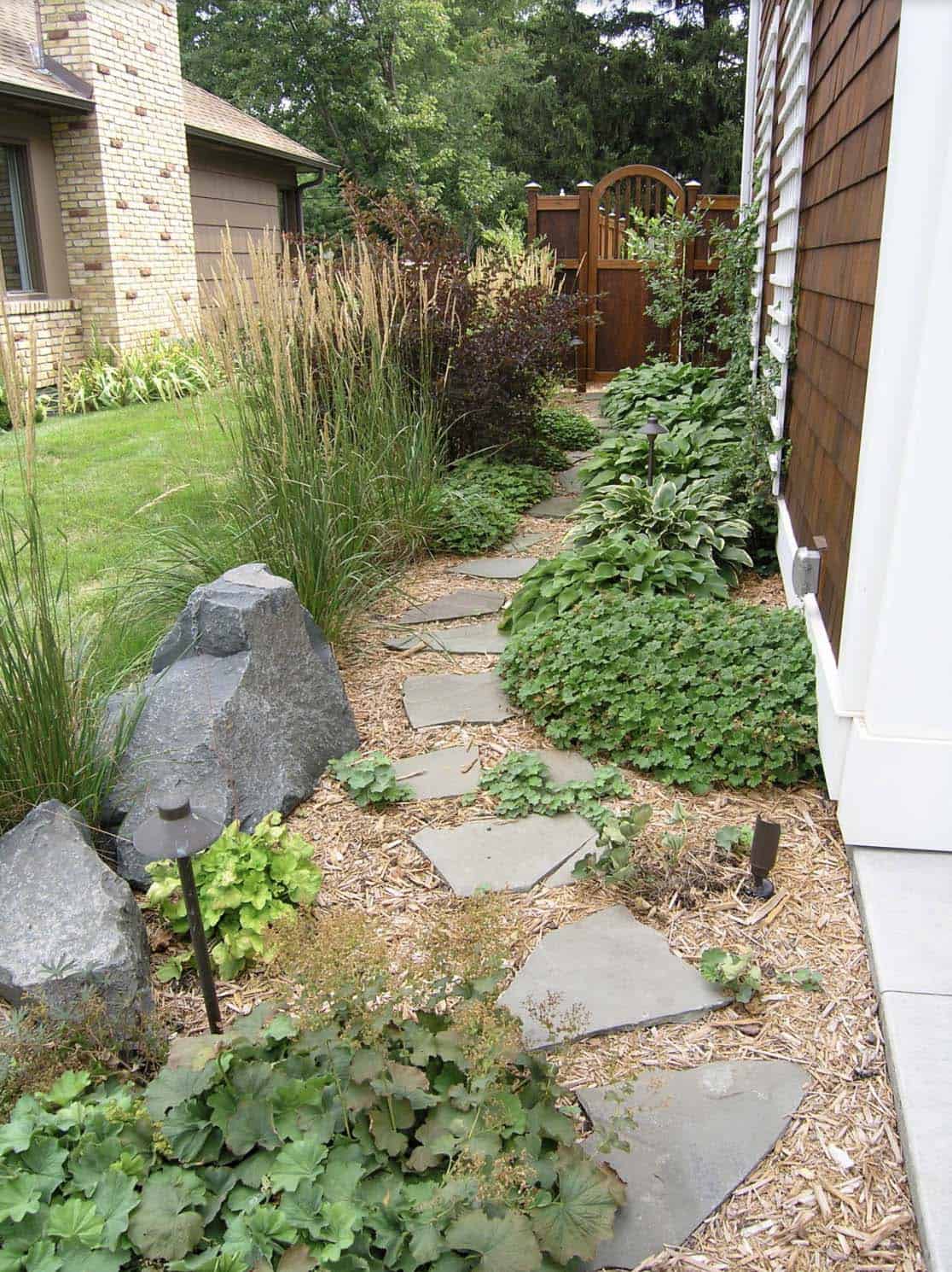 Narrow side yard with flagstone path, ornamental grasses, hostas, heuchera, and landscape lighting in Minneapolis