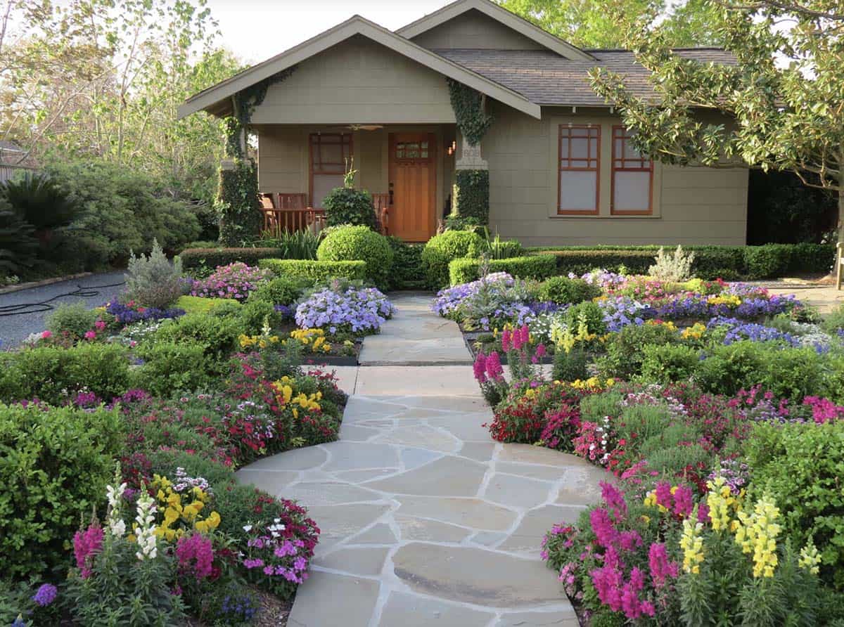 Cottage-style front yard with flagstone path, formal boxwood hedges, and colorful mixed flower borders