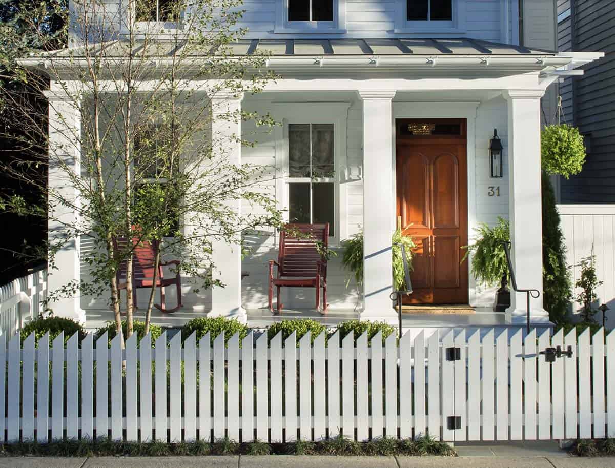 White Colonial Porch With Red Rockers, Wood Door, and Picket Fence