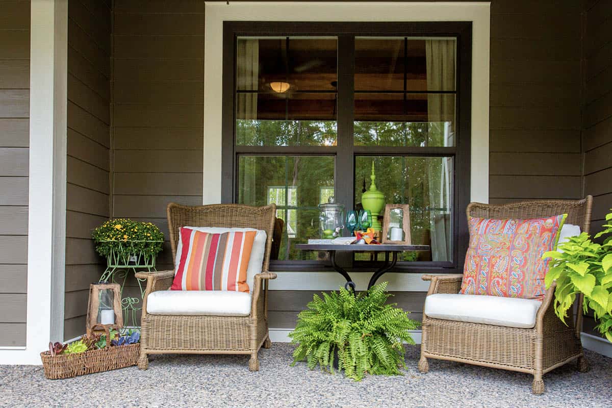 Wicker Lounge Chairs With Colorful Pillows and Fern on Dark Porch