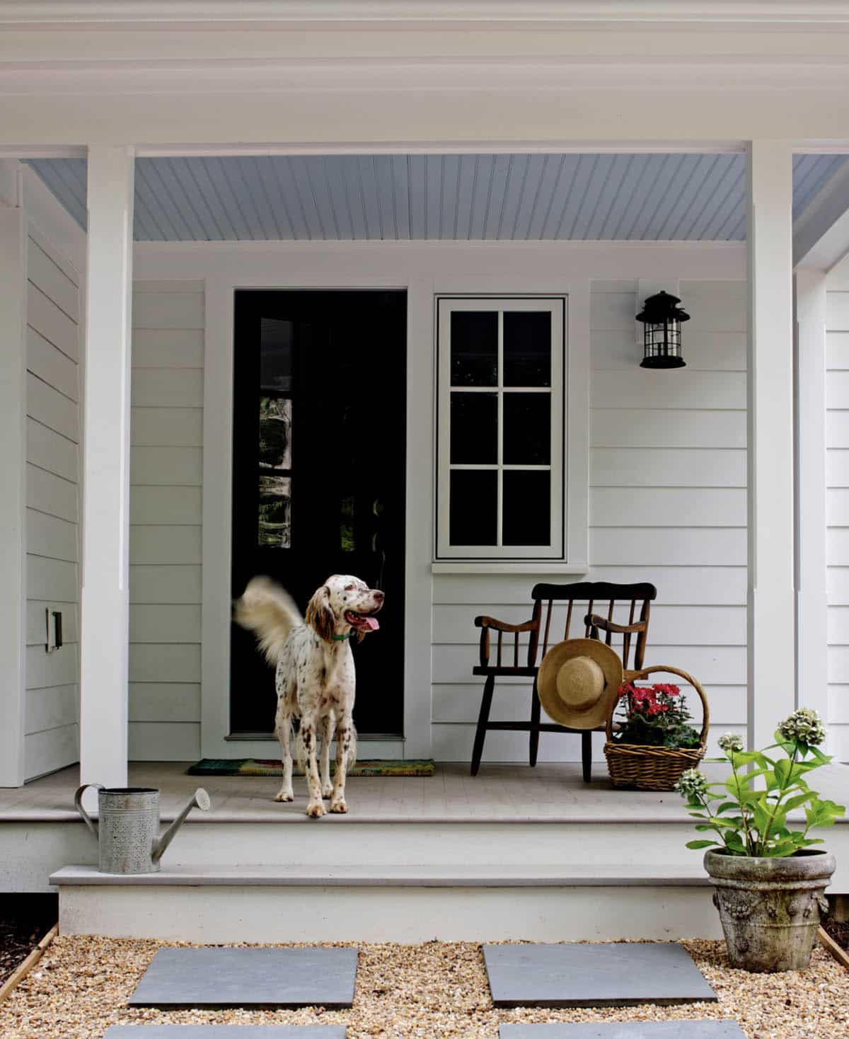 White Farmhouse Porch With Grey-Blue Beadboard Ceiling, Black Door, and Antique Chair