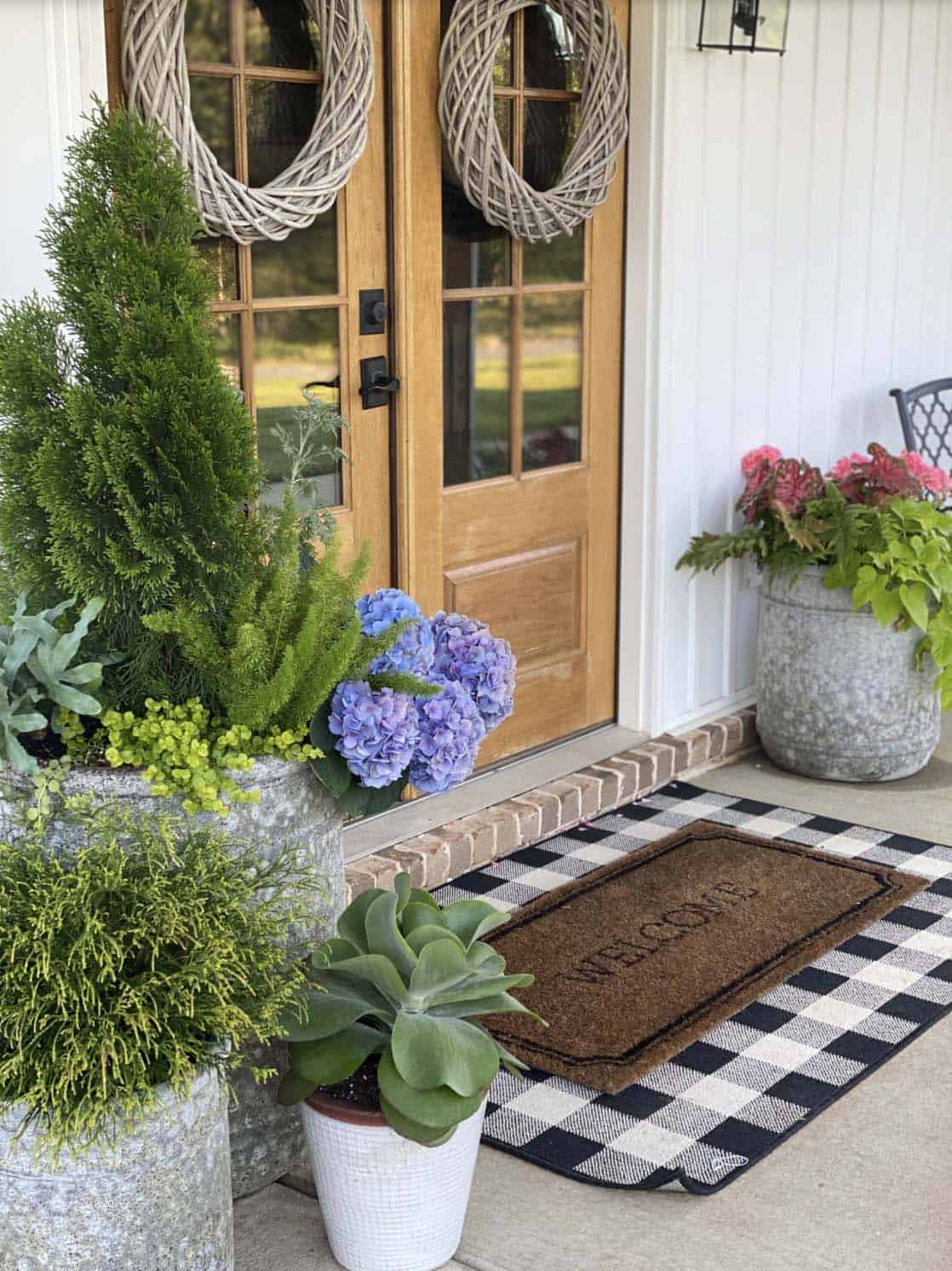 Wood French Doors With Grapevine Wreaths, Layered Doormats, and Galvanized Planters