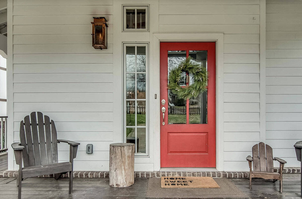 White Farmhouse Porch With Red Door, Evergreen Wreath, and Adirondack Chairs