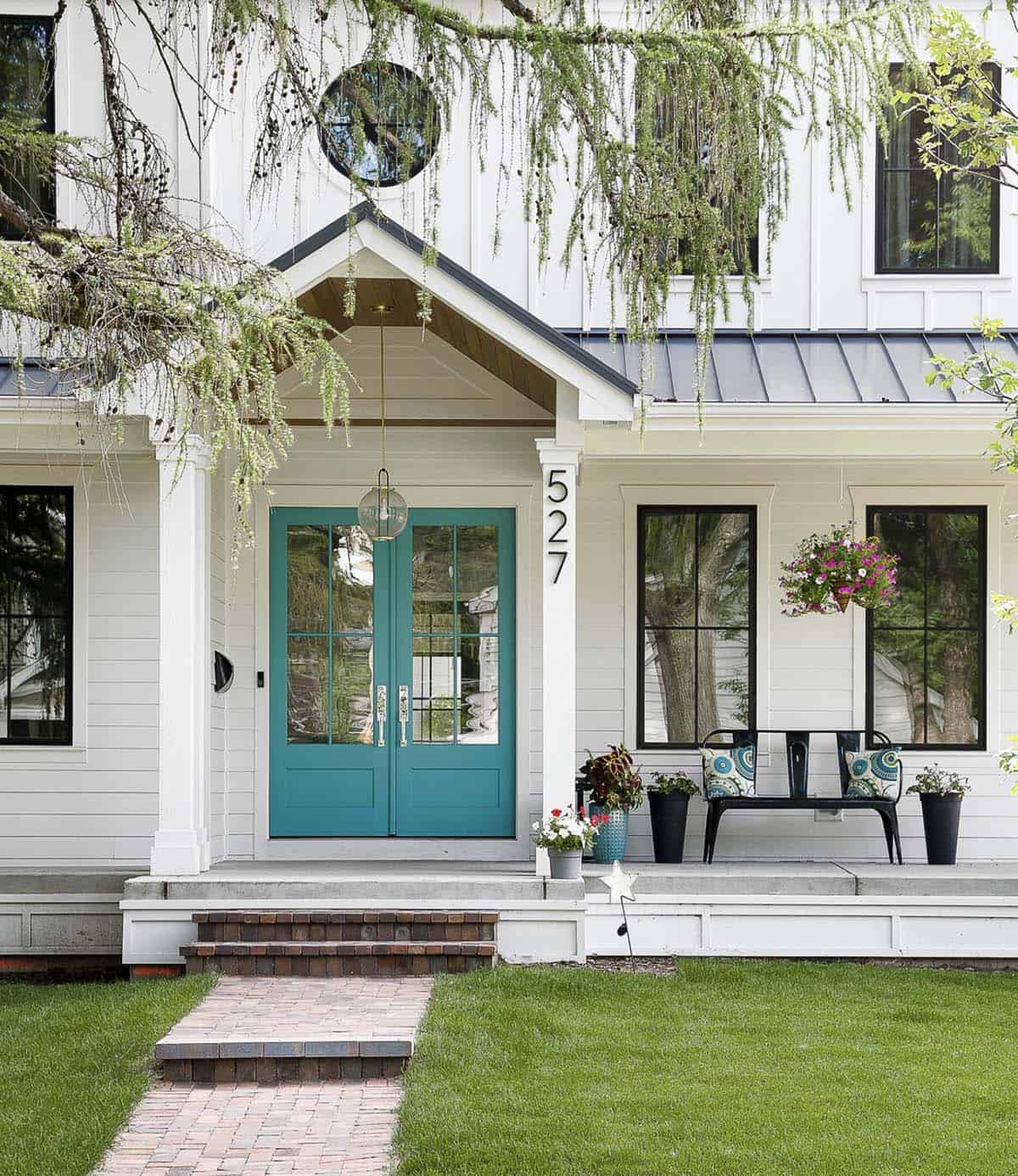 White Modern Farmhouse With Teal French Doors, Metal Roof, and Brick Pathway