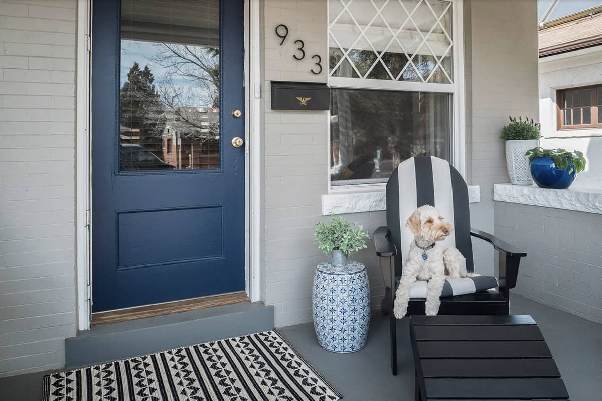 Grey Brick Porch With Navy Door, Striped Adirondack Chair, and Blue Garden Stool