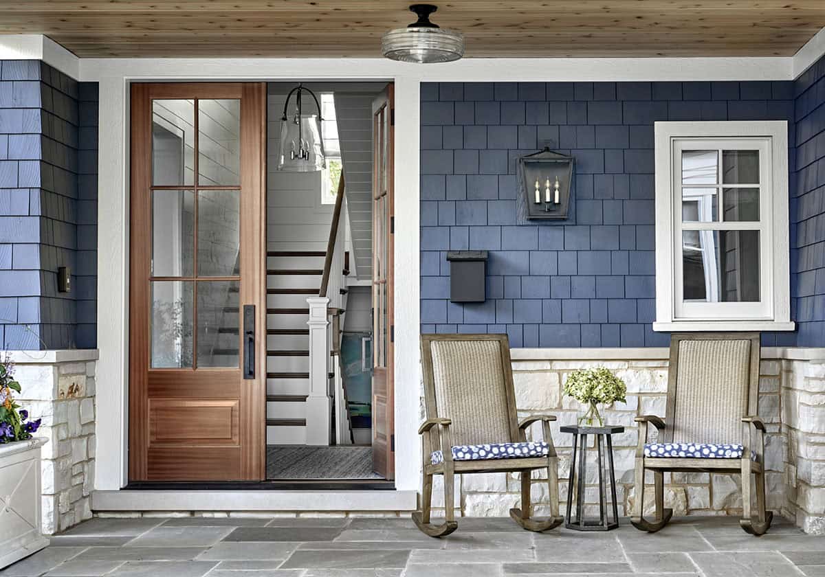 Blue Shingle Porch With Wood Door, Stone Base, and Wicker Rocking Chairs