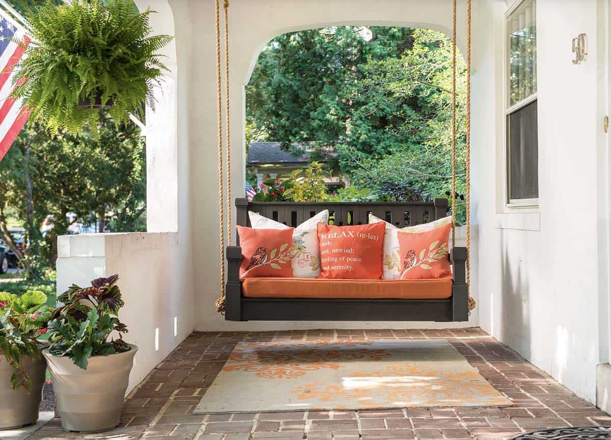 White Arched Porch With Dark Wood Rope Swing and Orange Cushions