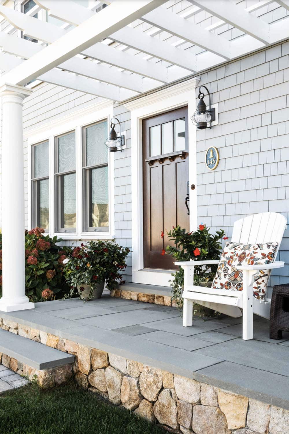 Grey Shingle Coastal Porch With White Pergola, Wood Door, and Adirondack Chair