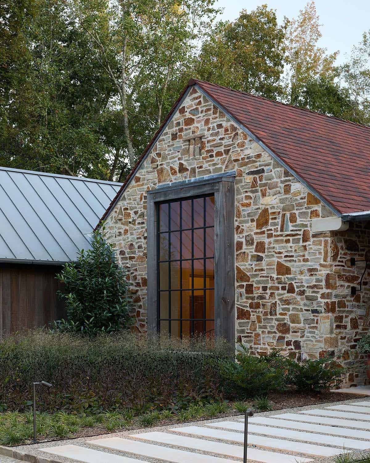 Close-up of stone gable exterior with tall steel-framed window and red tile roof