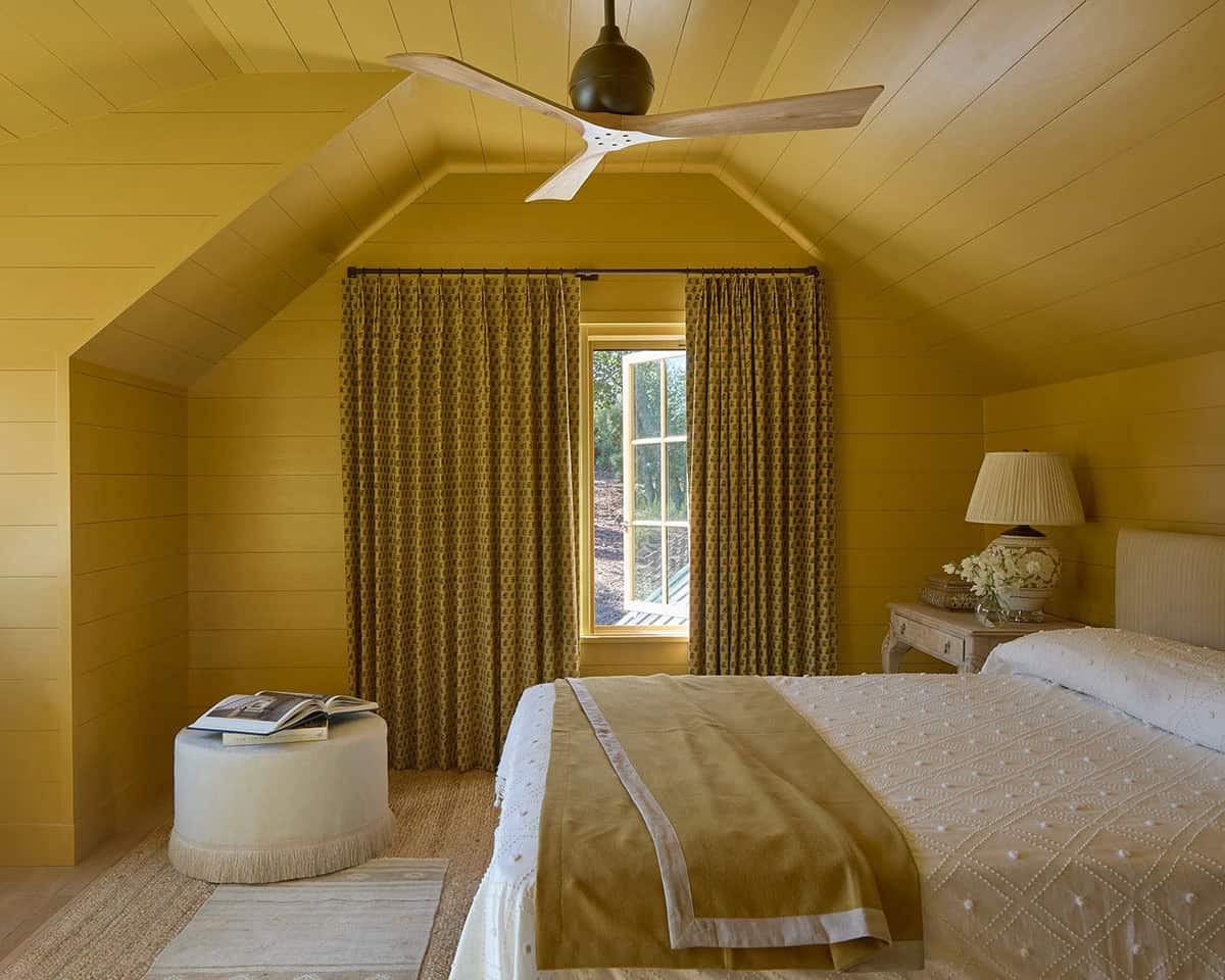 Guest bedroom with ochre yellow shiplap walls and ceiling, patterned curtains, and ceiling fan