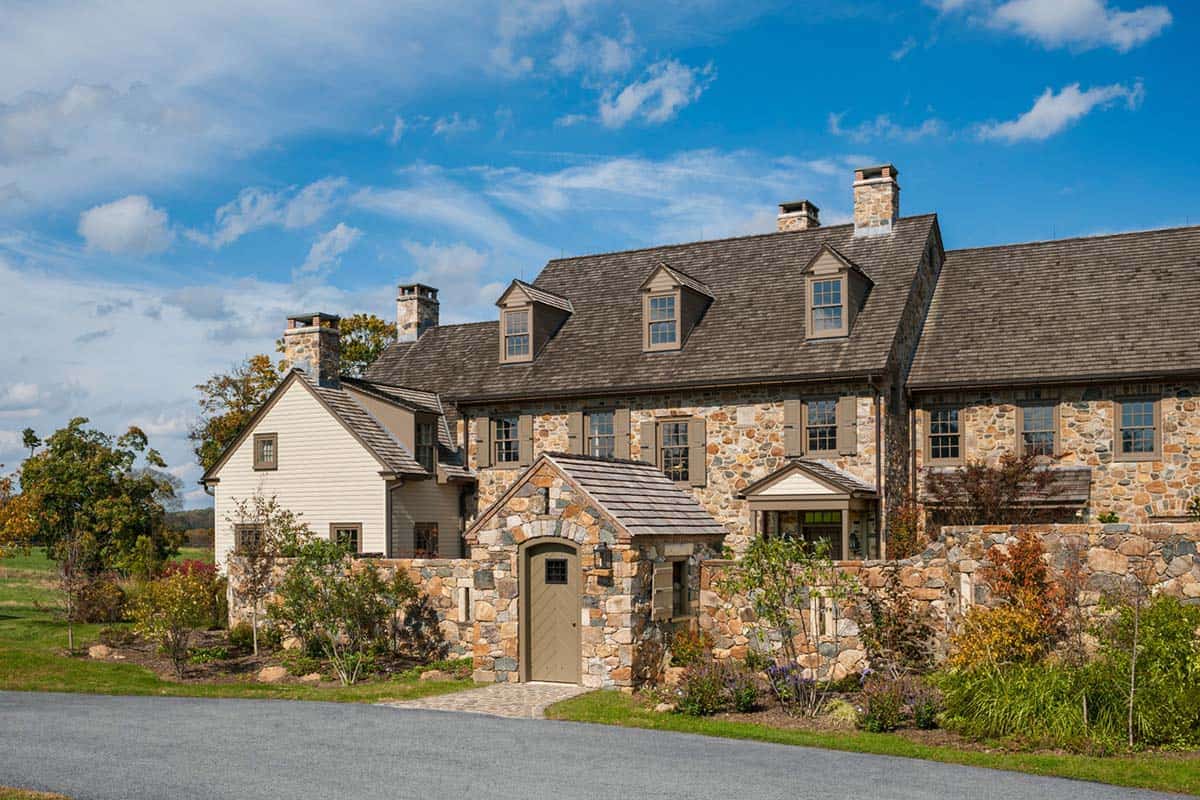 Close-up of fieldstone farmhouse facade with arched garden gate and dormer windows