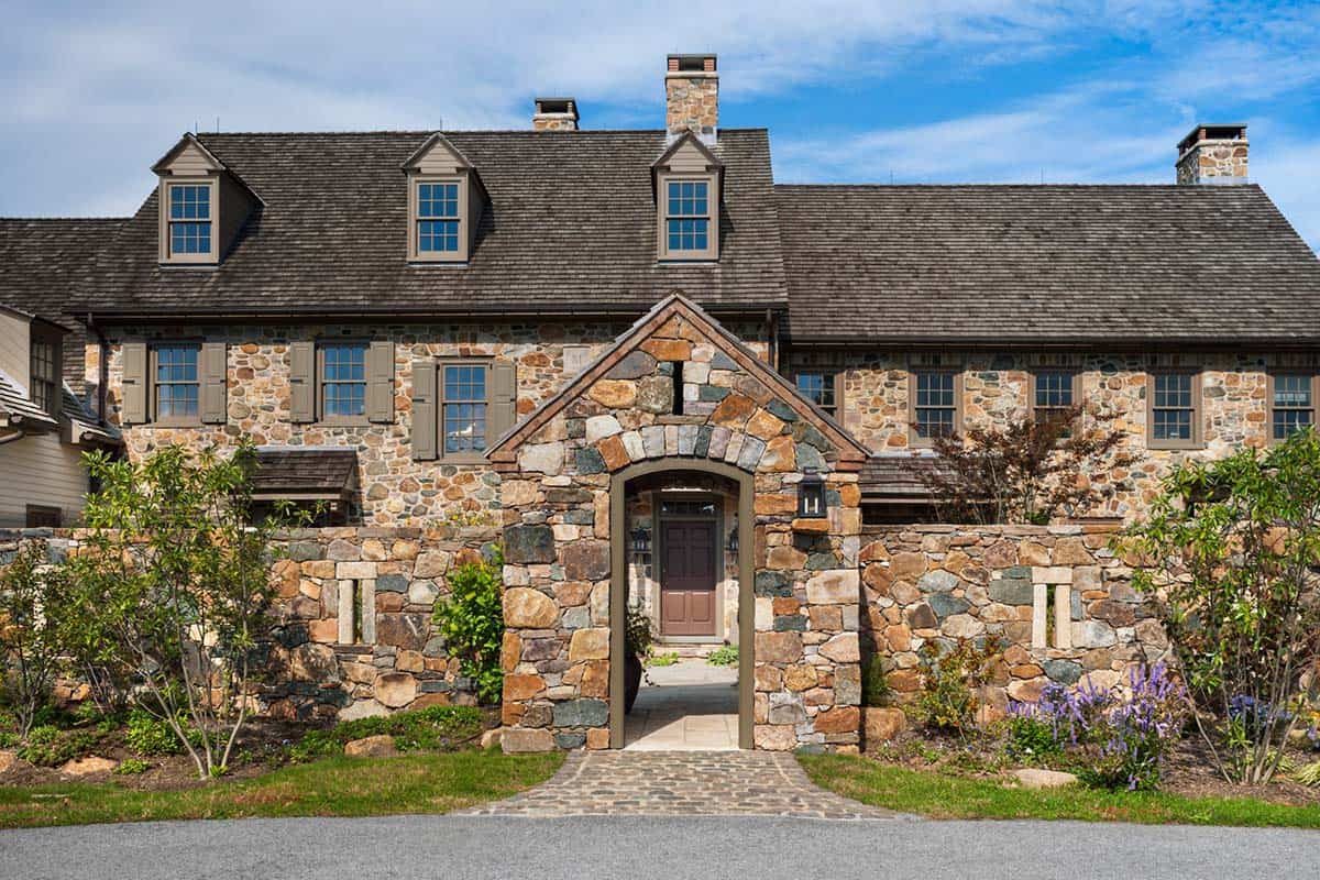 Fieldstone farmhouse front entry with arched stone gateway and cobblestone path