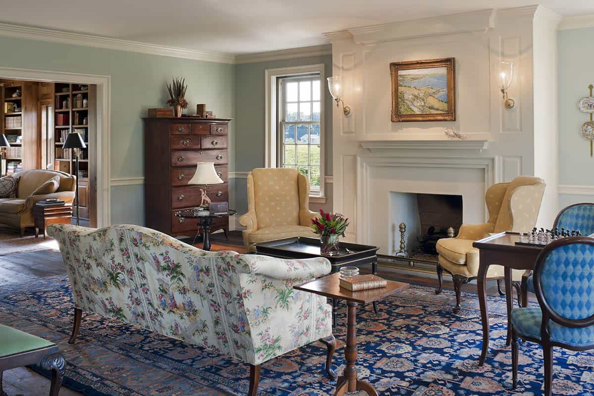 Formal living room with sage green walls, paneled fireplace surround, and antique furnishings