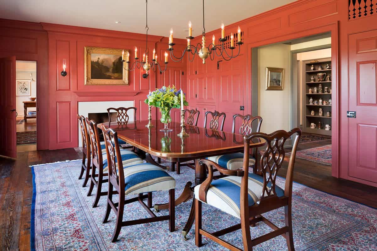 Colonial dining room with floor-to-ceiling red paneling, Chippendale chairs, and iron candle chandelier