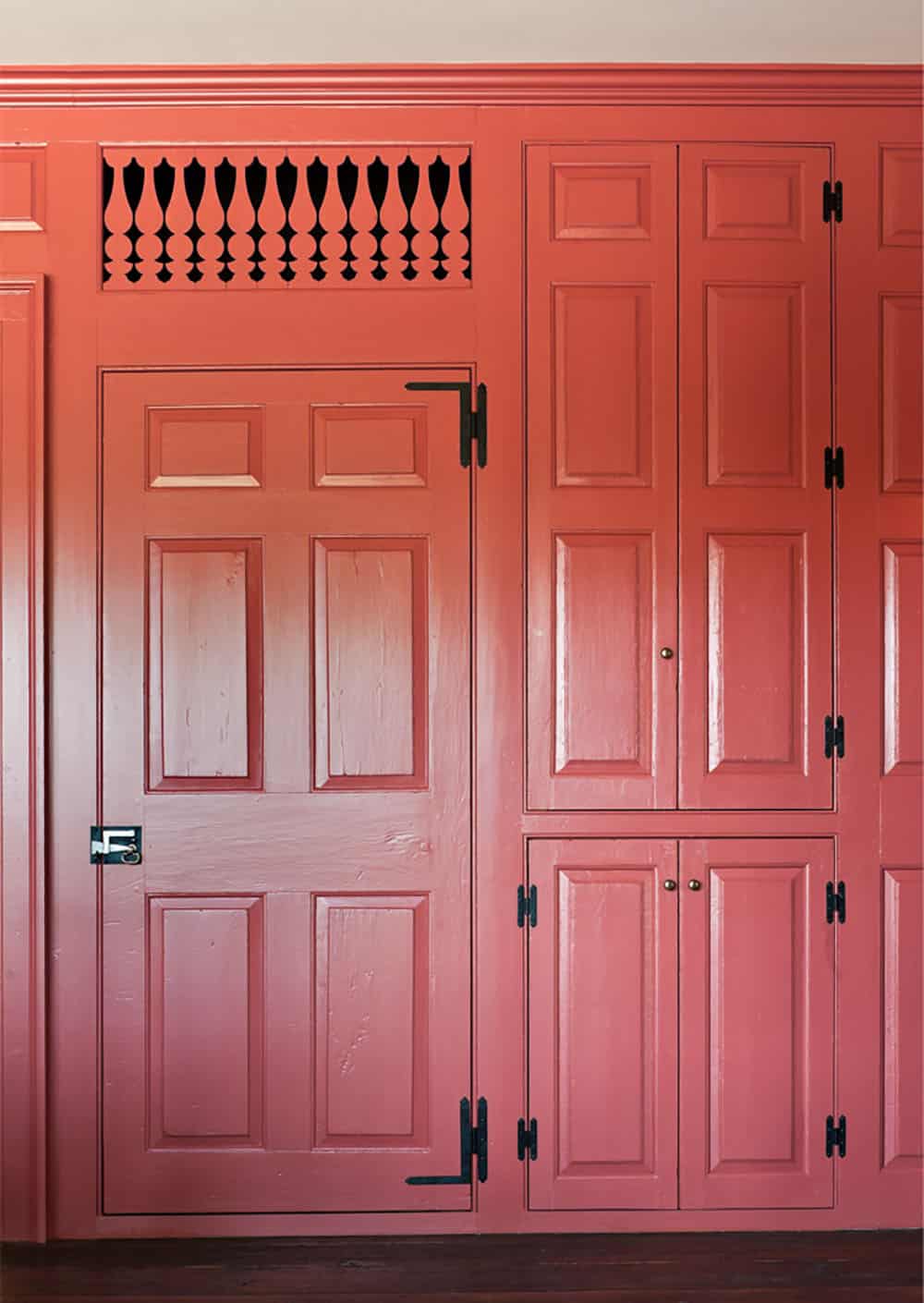 Red-painted paneled doors and cabinetry with decorative spindle transom grille