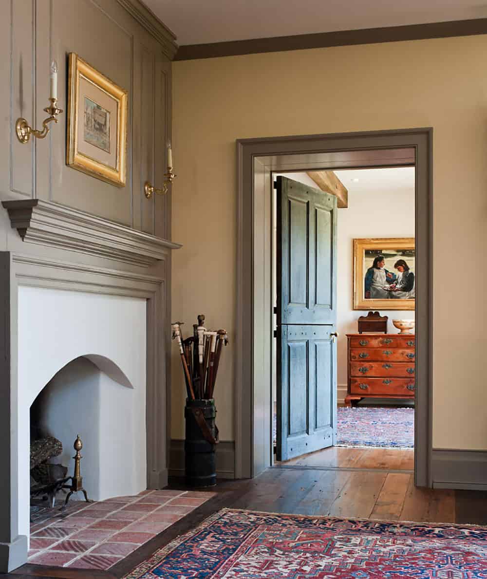 Entry hall fireplace and paneled mantel with view through open Dutch door to adjoining room